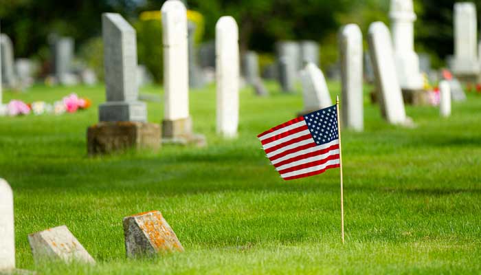 American flag placed at a burial site in a cemetery.